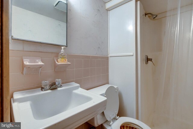 bathroom featuring sink, tile walls, and toilet