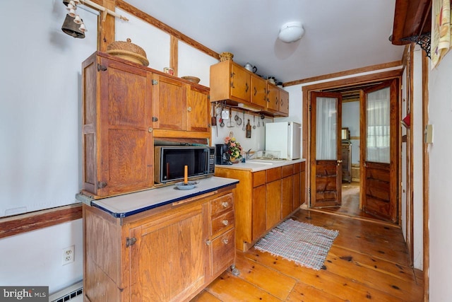 kitchen featuring sink, a baseboard radiator, light hardwood / wood-style floors, and white refrigerator