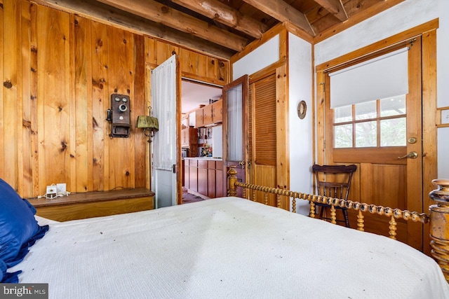 bedroom featuring beamed ceiling, wood walls, and a closet