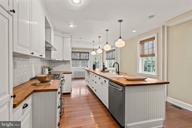 kitchen with sink, white cabinetry, light wood-type flooring, and butcher block countertops