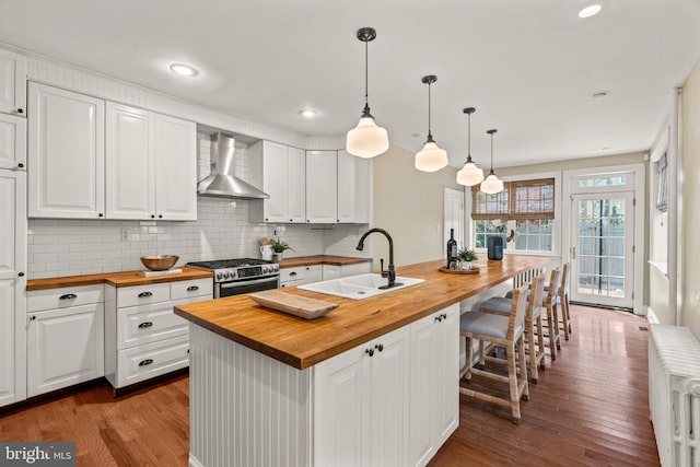 kitchen with wooden counters, hardwood / wood-style floors, sink, wall chimney exhaust hood, and stainless steel range with gas stovetop