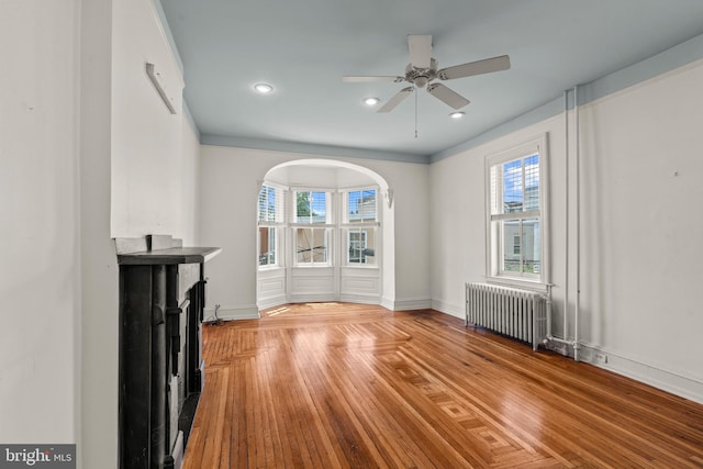 unfurnished living room featuring light hardwood / wood-style floors, ceiling fan, and radiator