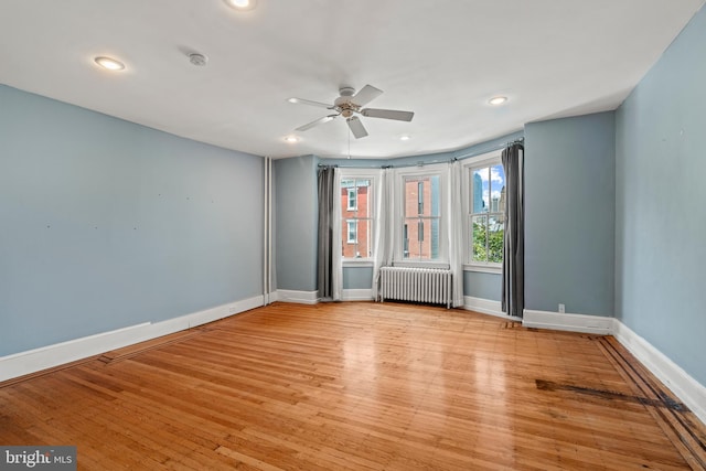 spare room featuring ceiling fan, light hardwood / wood-style flooring, and radiator heating unit