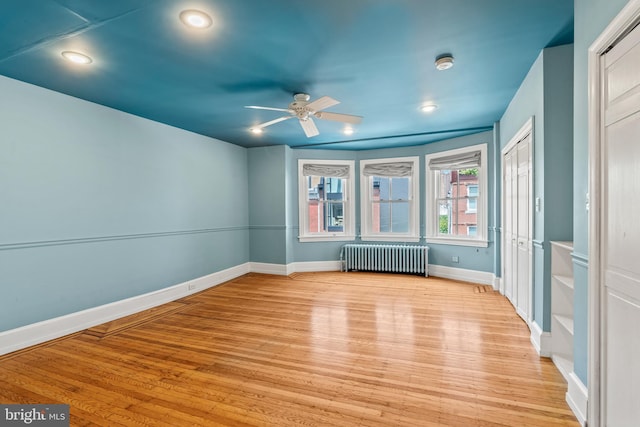 spare room featuring ceiling fan, light hardwood / wood-style floors, and radiator