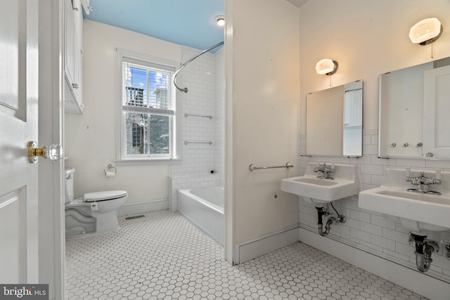 full bathroom with toilet, tasteful backsplash, tile patterned floors, sink, and tiled shower / bath combo