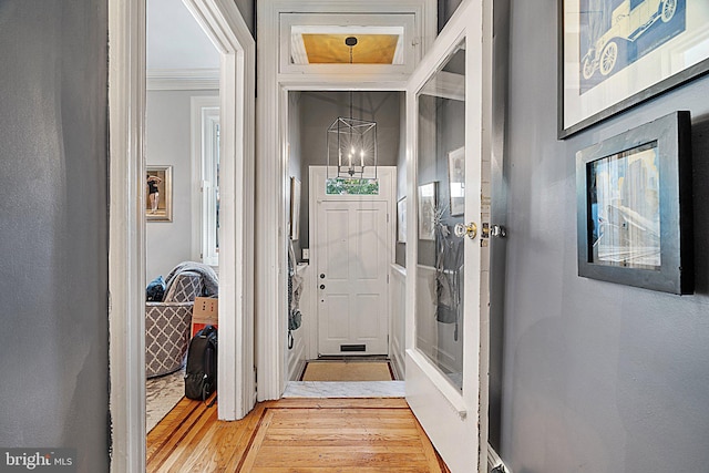 doorway with crown molding and light hardwood / wood-style flooring