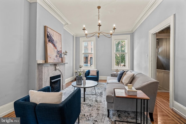 living room featuring crown molding, a high end fireplace, an inviting chandelier, and hardwood / wood-style flooring