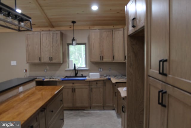 kitchen featuring decorative light fixtures, butcher block countertops, light brown cabinetry, wood ceiling, and sink