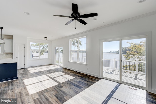 unfurnished living room with dark hardwood / wood-style flooring, ornamental molding, ceiling fan, and a water view