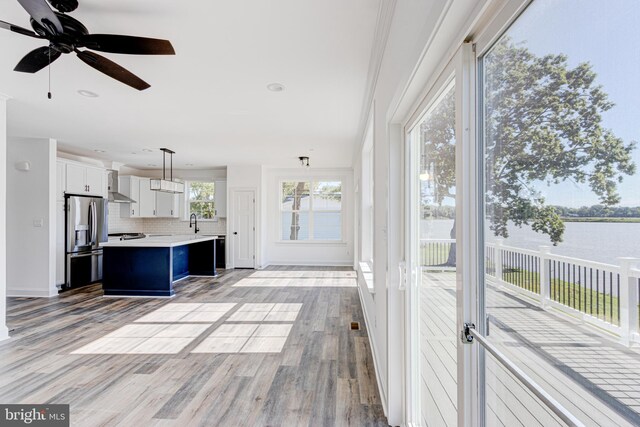 unfurnished sunroom featuring a water view, ceiling fan, and sink