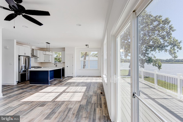 unfurnished sunroom with a water view, ceiling fan, and sink