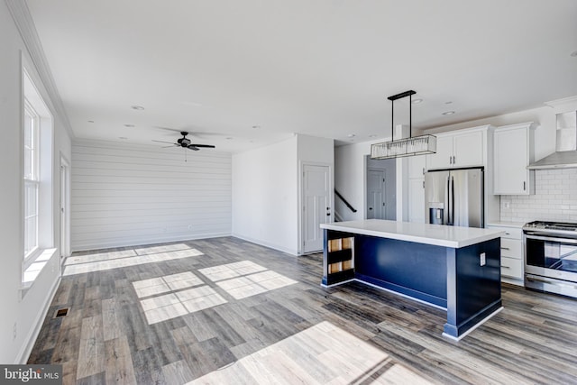 kitchen with wall chimney range hood, a breakfast bar, stainless steel appliances, a center island, and white cabinets