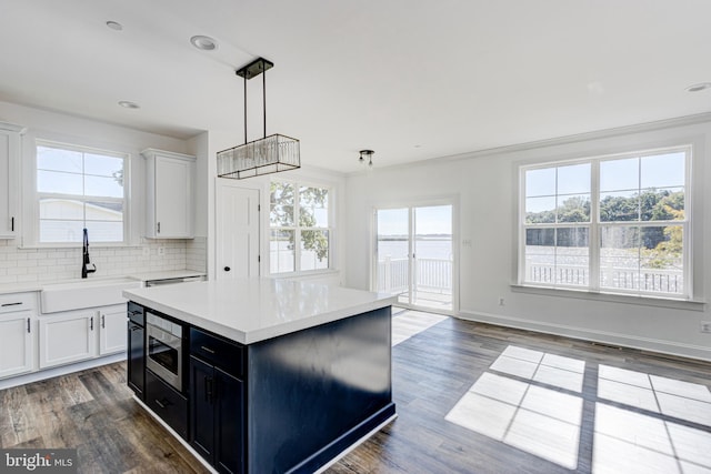 kitchen with pendant lighting, sink, white cabinetry, a center island, and tasteful backsplash