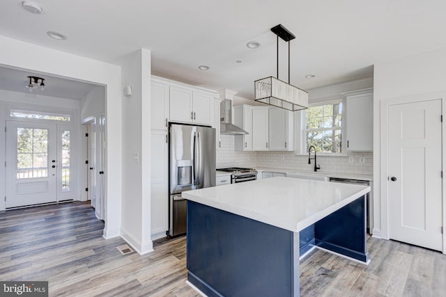 kitchen featuring sink, decorative light fixtures, a center island, stainless steel appliances, and white cabinets