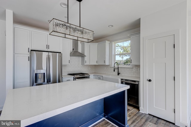 kitchen featuring a center island, wall chimney range hood, sink, and appliances with stainless steel finishes