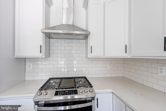 kitchen with stainless steel range with gas cooktop, tasteful backsplash, white cabinetry, light stone countertops, and wall chimney range hood