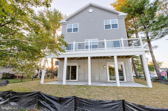 rear view of house with a balcony, a patio, and a lawn