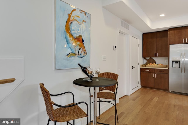 kitchen with stainless steel fridge with ice dispenser, dark brown cabinets, and light hardwood / wood-style floors