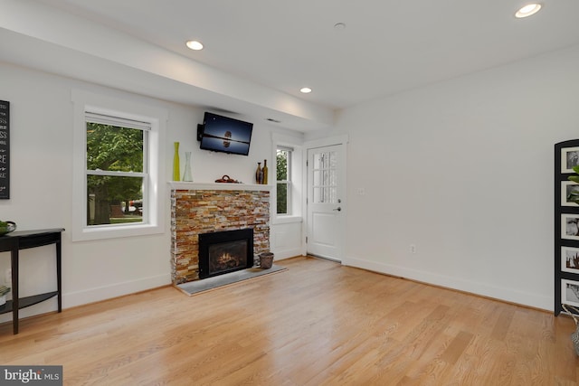 living room featuring a wealth of natural light, a fireplace, and light hardwood / wood-style flooring