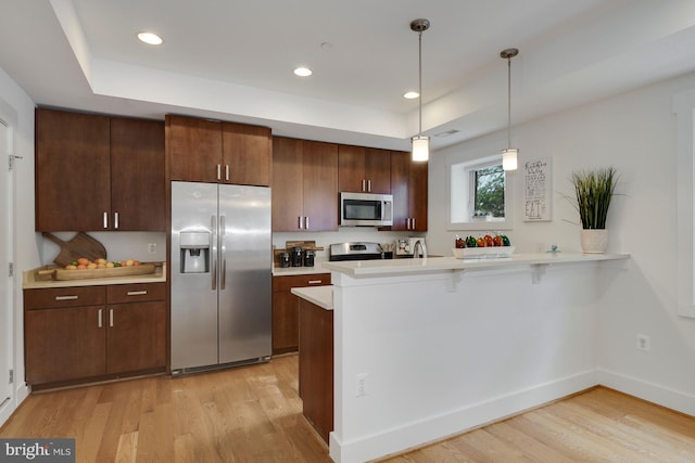 kitchen with decorative light fixtures, dark brown cabinets, light wood-type flooring, appliances with stainless steel finishes, and kitchen peninsula