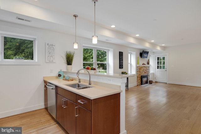 kitchen featuring sink, stainless steel dishwasher, light hardwood / wood-style floors, and kitchen peninsula