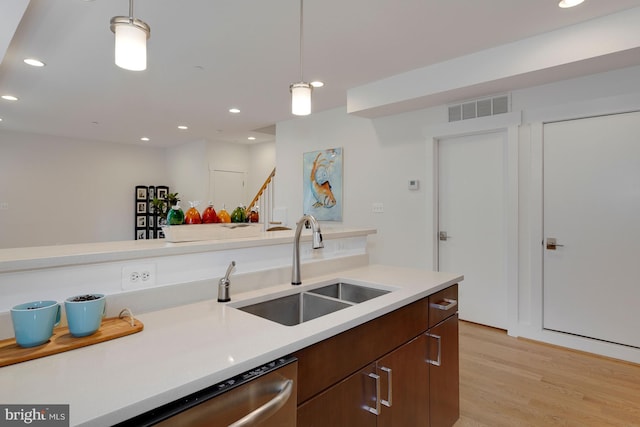 kitchen with pendant lighting, stainless steel dishwasher, sink, and light wood-type flooring