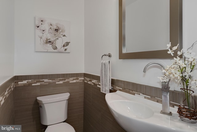 bathroom with tile walls, sink, and toilet