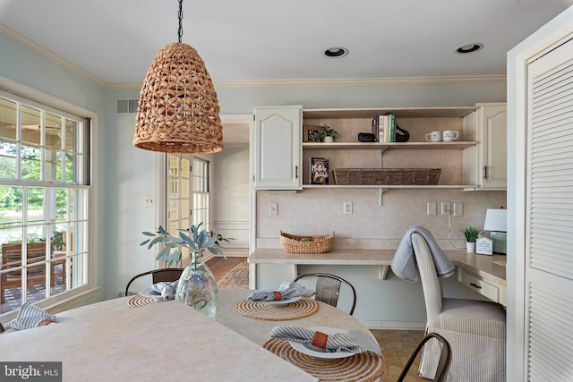 dining space featuring ornamental molding and built in desk