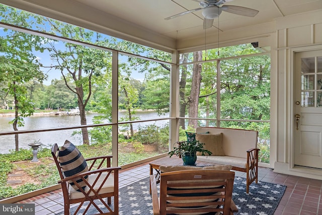 sunroom with ceiling fan and a water view