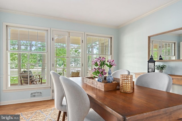 dining room with crown molding and light hardwood / wood-style flooring