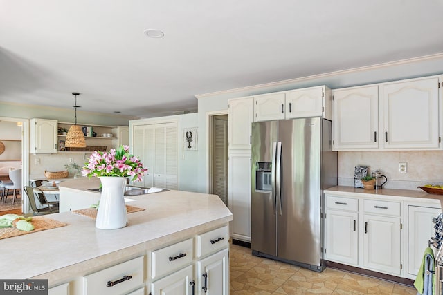 kitchen featuring white cabinetry, tasteful backsplash, decorative light fixtures, ornamental molding, and stainless steel fridge