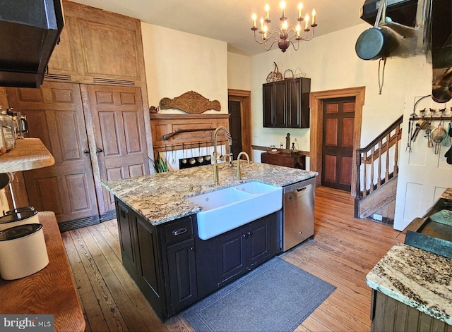 kitchen with light stone counters, sink, stainless steel dishwasher, a center island with sink, and light hardwood / wood-style floors