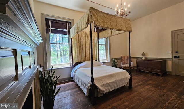 bedroom with an inviting chandelier and dark hardwood / wood-style floors