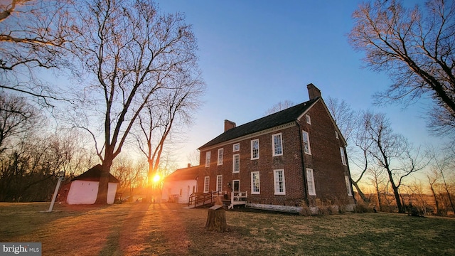 property exterior at dusk featuring a lawn and a deck