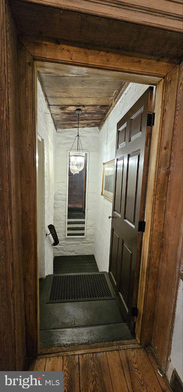 corridor with wood-type flooring, a chandelier, and wooden ceiling