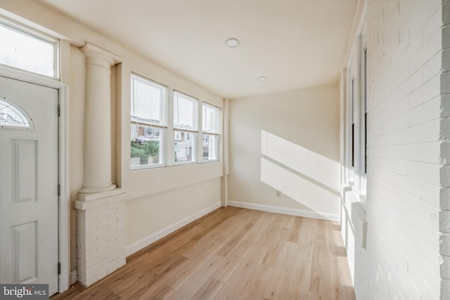 foyer featuring ornate columns and light wood-type flooring