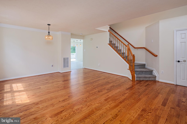 unfurnished living room with crown molding and light wood-type flooring