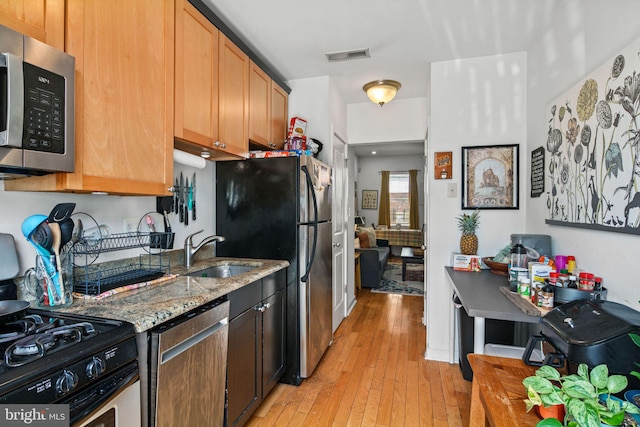 kitchen featuring light hardwood / wood-style floors, stainless steel appliances, light stone countertops, and sink