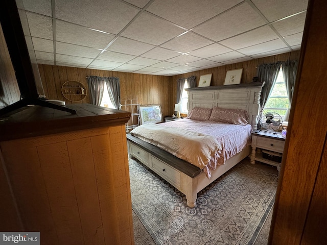 bedroom featuring wood walls and a paneled ceiling