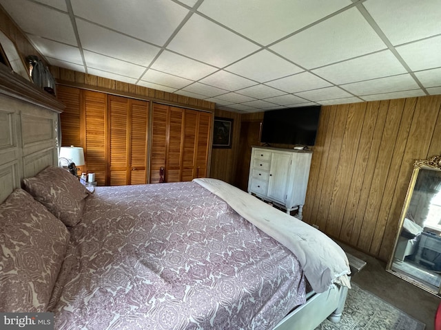 unfurnished bedroom featuring wood walls, a closet, and a paneled ceiling