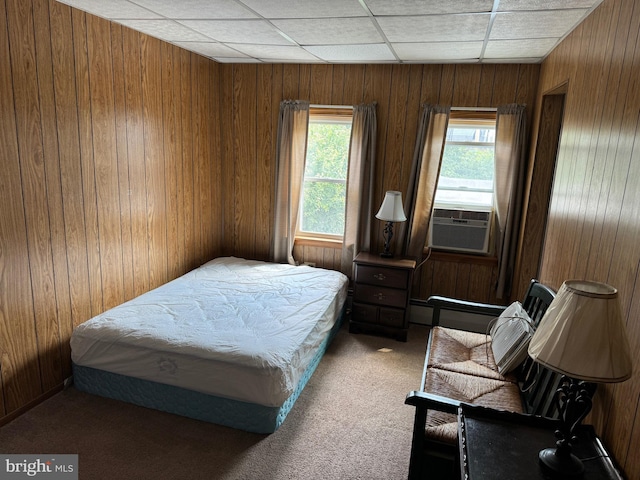 bedroom with carpet floors, wood walls, baseboard heating, cooling unit, and a drop ceiling