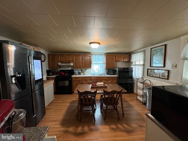 kitchen with stainless steel fridge, sink, black range, electric range, and light hardwood / wood-style floors