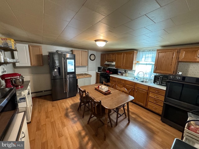 kitchen featuring black appliances, a baseboard heating unit, sink, and light hardwood / wood-style flooring