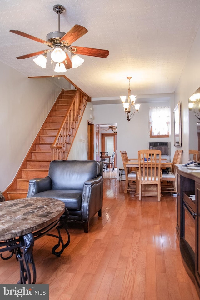 living room with ceiling fan with notable chandelier and light hardwood / wood-style floors