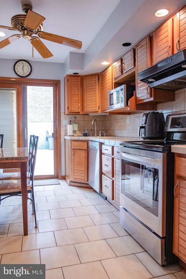 kitchen featuring light tile patterned flooring, ceiling fan, appliances with stainless steel finishes, and tasteful backsplash