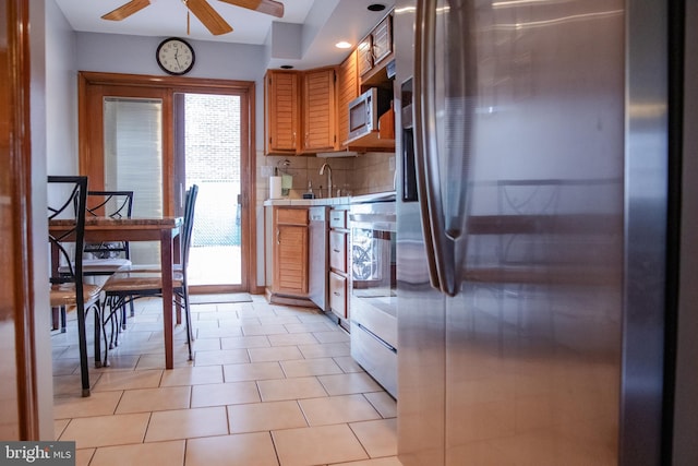 kitchen with light tile patterned flooring, ceiling fan, decorative backsplash, sink, and appliances with stainless steel finishes