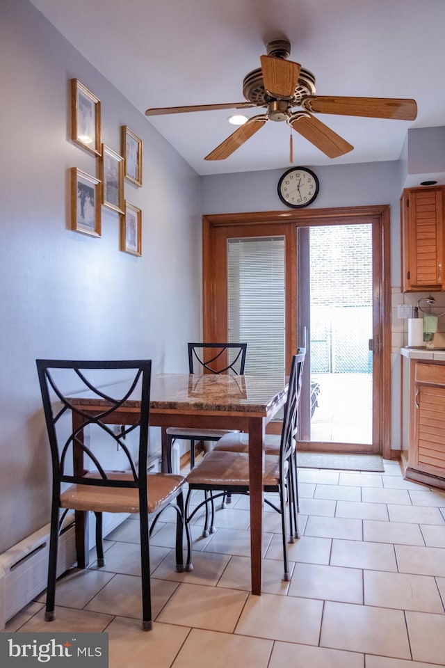 tiled dining room with a baseboard heating unit and ceiling fan