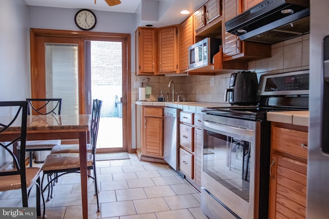 kitchen with stainless steel appliances, a wealth of natural light, tasteful backsplash, and light tile patterned floors