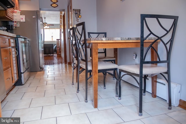 dining area featuring baseboard heating, light tile patterned floors, and ceiling fan