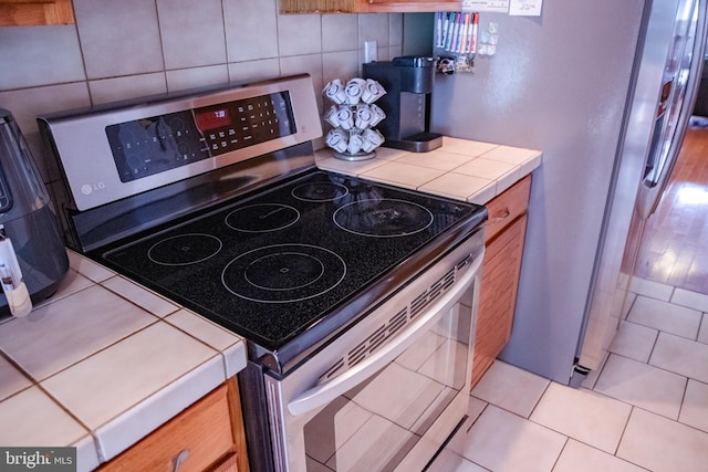 kitchen with appliances with stainless steel finishes, light tile patterned flooring, and tile counters